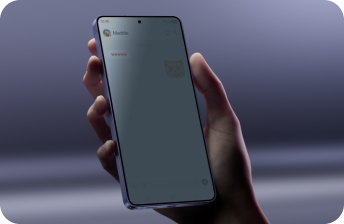 Osoba trzyma smartfon z widocznym ekranem, na którym wyświetlona jest aplikacja do wiadomości z tekstem \'Maddie\' i emotikoną kota. Tło jest rozmyte i ma fioletowy odcień.