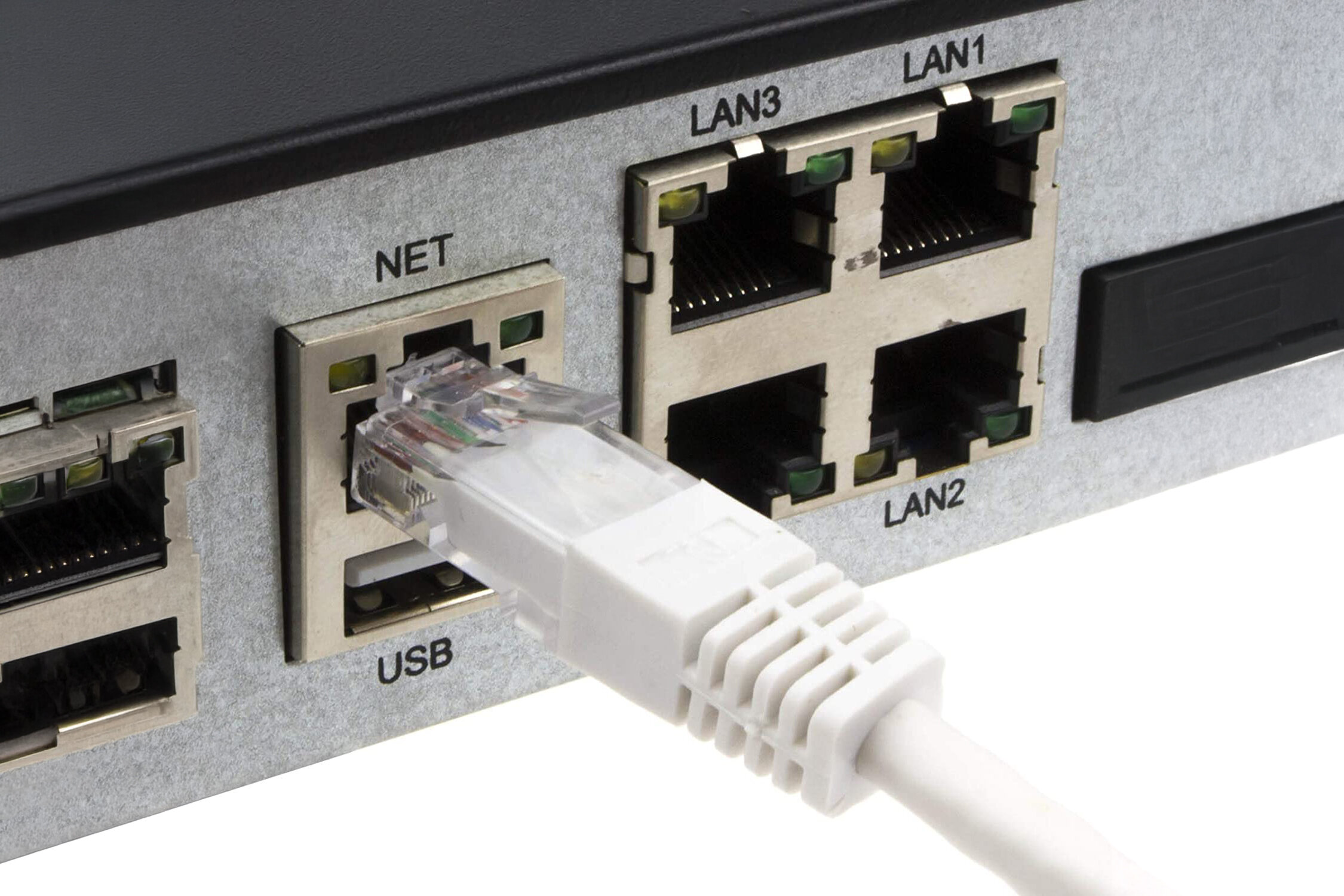 Zdjęcie przedstawia panel z portami sieciowymi, do którego podłączony jest biały kabel RJ-45. Widoczne są oznaczenia portów: NET, USB, LAN3, LAN1, LAN2.