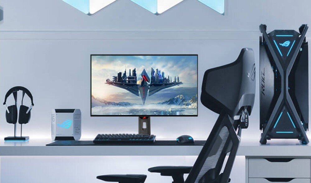 Monitor ASUS ROG Strix XG27AQDMG Stanowisko do gier z monitorem na środku, futurystyczną jednostką centralną po prawej i podświetlanymi akcesoriami na biurku. Na ekranie widoczna grafika z futurystycznym statkiem, jednolita jasność