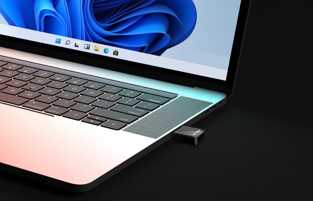 Karta sieciowa TENDA U11 Zbliżenie na bok laptopa z systemem Windows 11. Do jednego z portów USB podłączony jest mały adapter sieciowy marki Tenda, wygląd, wykonanie