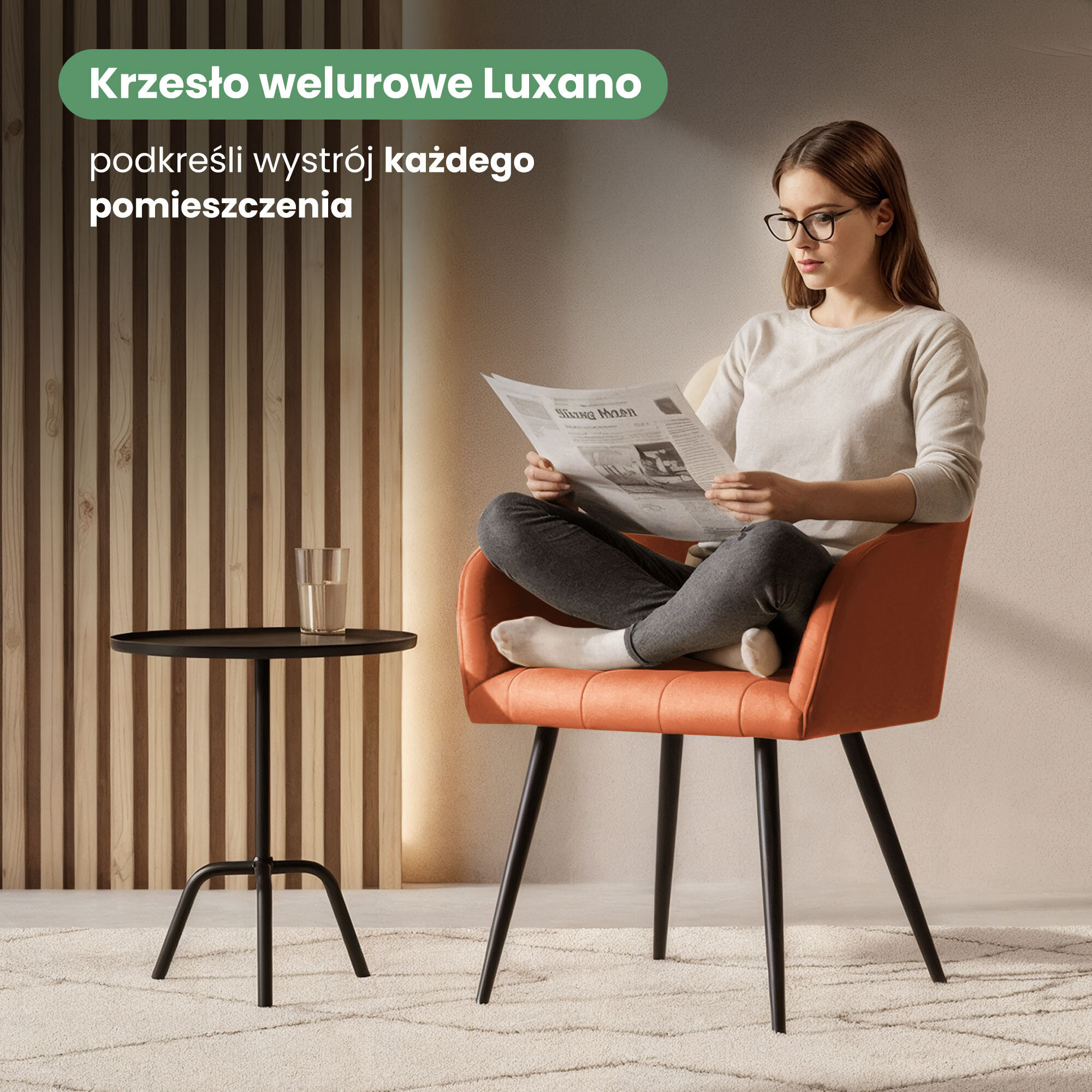 Osoba siedzi na pomarańczowym krześle z czarnymi nogami, trzymając gazetę. Obok znajduje się mały, czarny stolik z szklanką, a w tle widoczna jest drewniana ściana z pionowymi panelami.