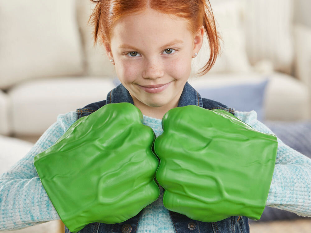 Rękawice HASBRO Marvel Avengers Gamma Smash Pięści Hulka F93325L0 Dziecko bawi się rękawicami Hulka, imitując walkę superbohaterów. Miękkie, zielone pięści są bezpieczne do zabawy w uderzanie i miażdżenie. Zdjęcie na jasnym tle z błękitnymi akcentami graficznymi.