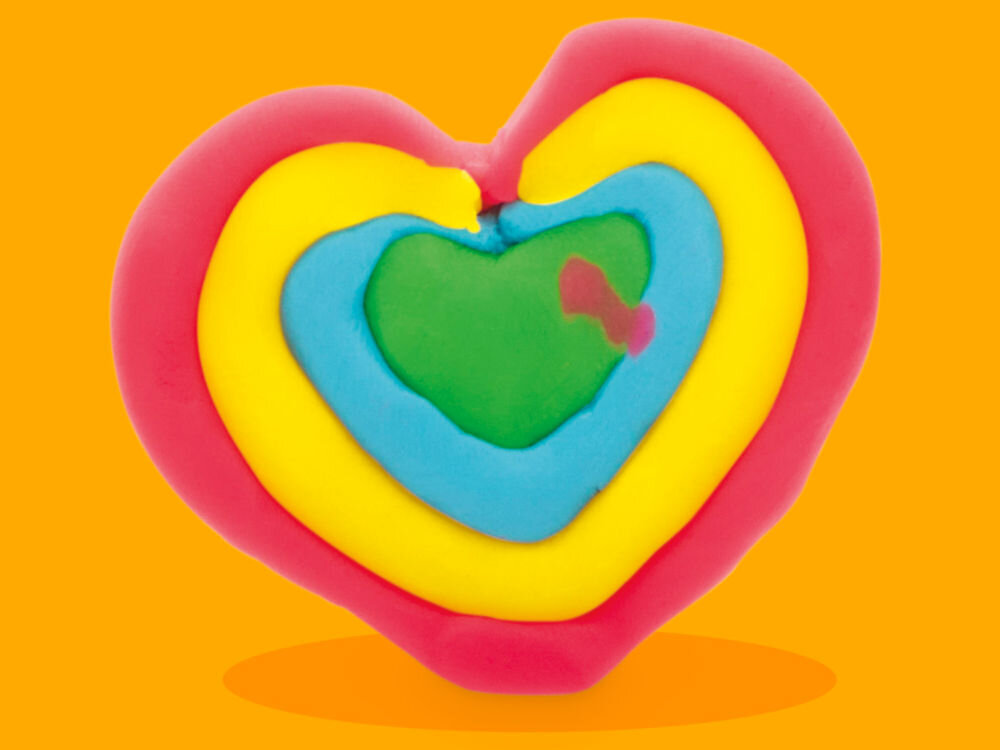 Ciastolina PLAY-DOH Zestaw startowy B11695L0 Wielokolorowe serce ulepione z warstw ciastoliny Play-Doh w kolorach czerwonym, żółtym, jasnoniebieskim i zielonym, umieszczone centralnie na pomarańczowym tle.