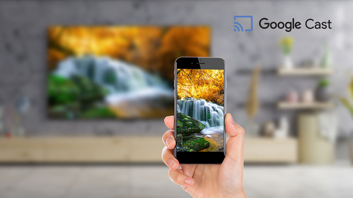 Telewizor SHARP 50HR8765E Google Cast, przesyłanie obrazu, filmy, zdjęcia, prezentacje, bez kabli, ręka trzymająca smartfon w ręku, telewizor zawieszony na ścianie nad komodą