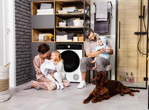 Rodzina składająca się z 4 osób i pies spędzają razem czas w łazience obok suszarki marki Amica