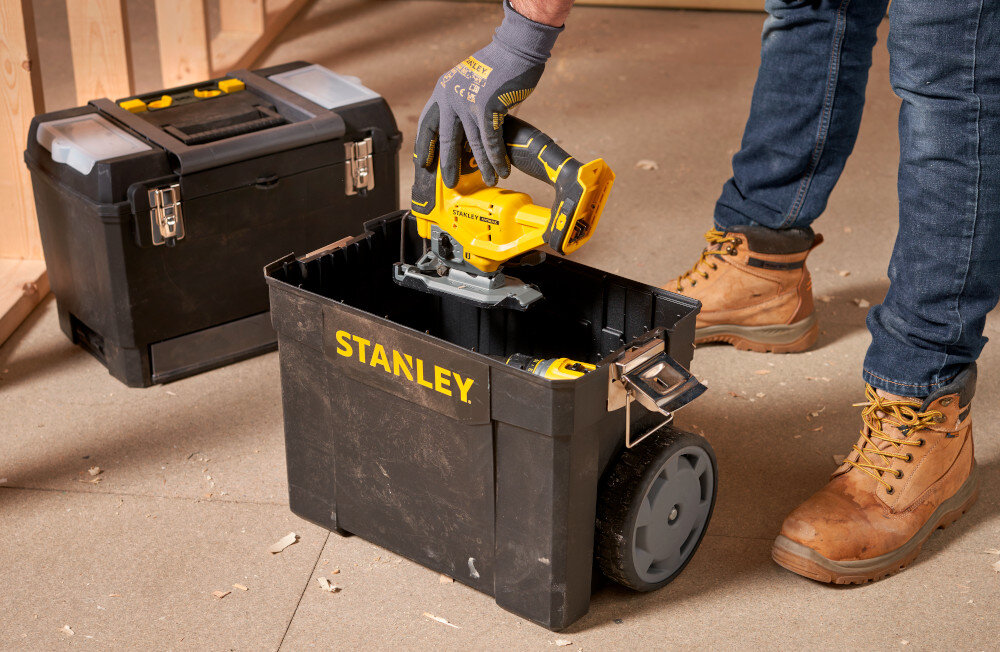 Skrzynka narzędziowa STANLEY 1-93-968 pomieszczenie skrzynki ustawione na podłodze osoba wyciąga z dolnej skrzynki narzędzie w tle drewniana ściana dolny moduł umożliwia przechowywanie większych narzędzi i materiałów otwarta konstrukcja wygodniejsze wyjmowanie sprzętu