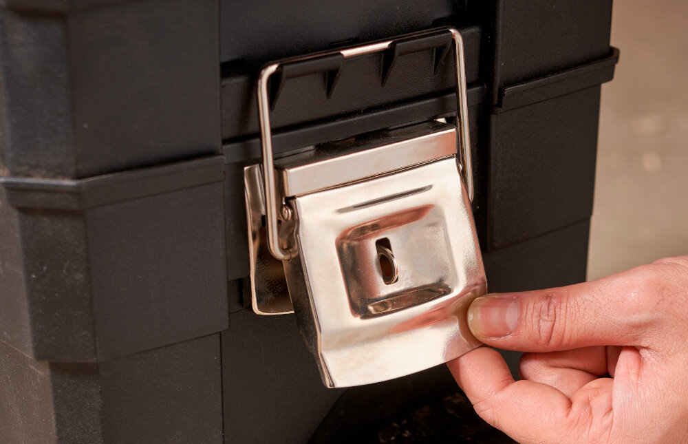 Skrzynka narzędziowa STANLEY 1-93-968 zbliżenie na zawiasy osoba trzyma zawias w dłoni metalowe zatrzaski solidne zawiasy z tworzywa sztucznego wysokiej jakości stabilność konstrukcji odporność na częste otwieranie narzędzia są zabezpieczone przed wypadnięciem uszkodzeniem