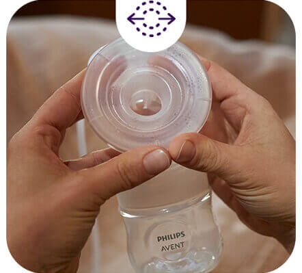 Osoba trzyma przezroczysty element laktatora z widocznym logo \'PHILIPS AVENT\'. Na górze obrazu znajduje się ikona z dwoma strzałkami skierowanymi w przeciwnych kierunkach.