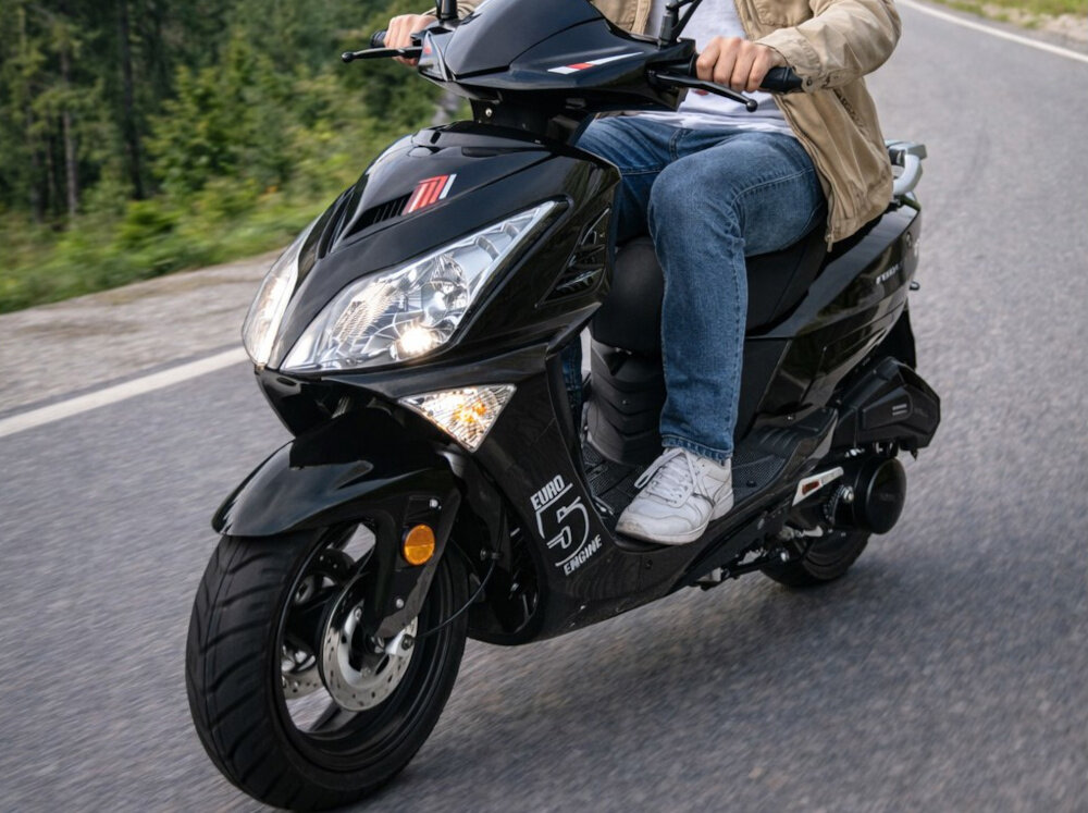 Motocykl ZNEN ZNAT125 (ZN125T-8F) Formax 125cm3 13 cali 5.5l Czarny osoba jedzie na motocyklu pośrodku ulicy Jednostka czterosuwowa o pojemności 124,6 cm³ rozwija moc 7,34 KM Chłodzenie powietrzem pojemność 5,5 l