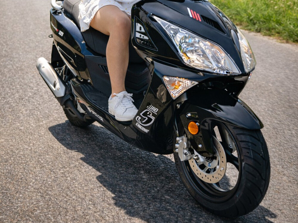 Motocykl ZNEN ZNAT125 (ZN125T-8F) Formax 125cm3 13 cali 5.5l Czarny osoba jedzie na motocyklu pośrodku ulicy Przedni widelec teleskopowy tylne podwójne elementy resorująco-tłumiące kontakt kół z nawierzchnią stabilne prowadzenie