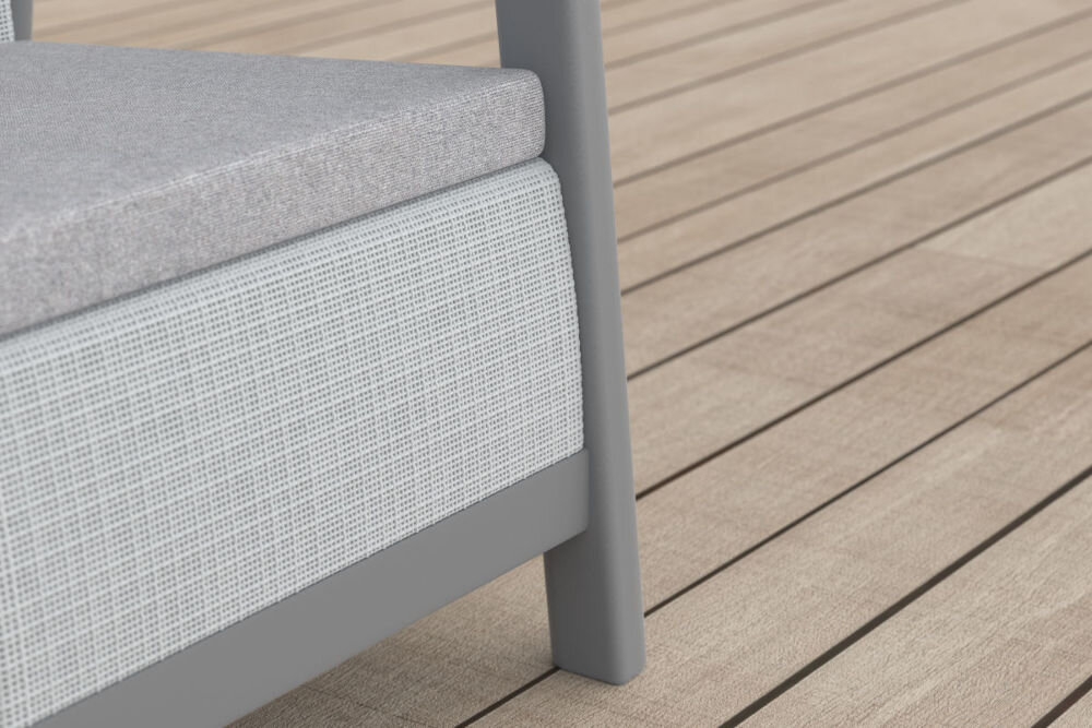 Fragment jasnoszarego mebla ogrodowego z poduszką na siedzisku, ustawionego na drewnianej podłodze tarasowej.