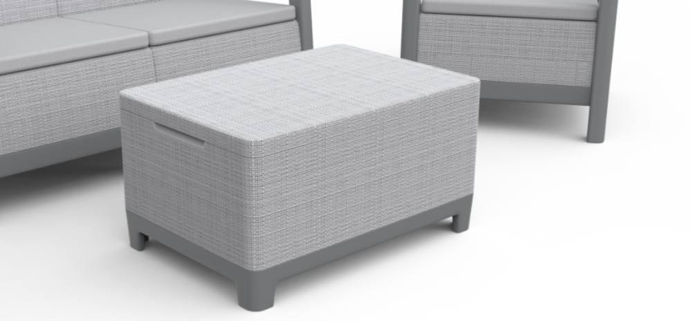 Na obrazie widoczny jest jasnoszary stolik ogrodowy z plecionką, będący częścią zestawu mebli. W tle znajdują się fragmenty kanapy i fotela o podobnym wzorze.