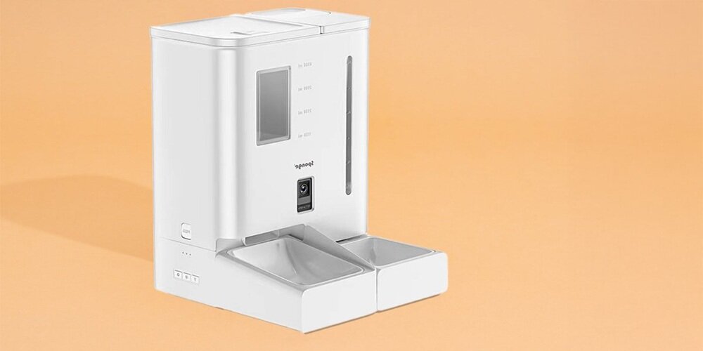 Biały automatyczny dozownik karmy z dwoma miseczkami na pomarańczowym tle. Na urządzeniu widoczne są oznaczenia poziomu oraz logo \'spongE\'.