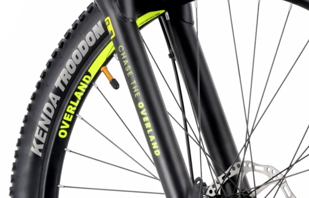 Rower górski MTB TATRA Overland U21 29 cali Niebiesko-limonkowy zbliżenie na oponę białe tło opony marki KENDA w rozmiarze 29 cali głęboki bieżnik skutecznie wspiera jazdę ułatwia utrzymanie stabilnego toru jazdy aluminiowe obręcze stalowe piasty marki Ciclo Sport regularne sprawdzanie ciśnienia powietrza wartość na bocznej części opony
