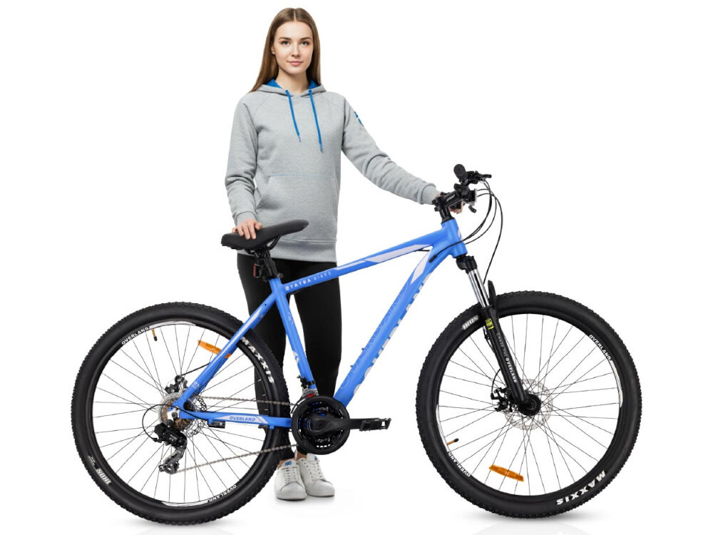 Rower górski MTB TATRA Overland U19 27.5 cala Niebieski białe tło osoba stoi za rowerem trzyma dłnie na siodełku i kierownicy 17-calowa aluminiowa rama rower jest bardzo zwinny lekki (17,5 kg) łatwo podnieść go by odporność na korozję wybór rozmiaru ramy Twój wzrost mierzony w zrelaksowanej pozycji typ roweru dla dzieci o wzroście od 165 do 174 cm