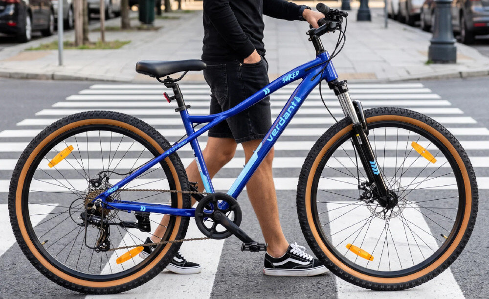 Rower górski MTB SUN BABY Verdant Shred D03.03.11.5.1.2 U19 29 cali Niebieski ulica osoba przechodzi przez przejście dla pieszych prowadzi obok rower dwuelementowa korba SBB wolnobieg marki Shunfeng 7 speed odpowiedni bieg płynniejsza jazda wygodne utrzymanie tempa