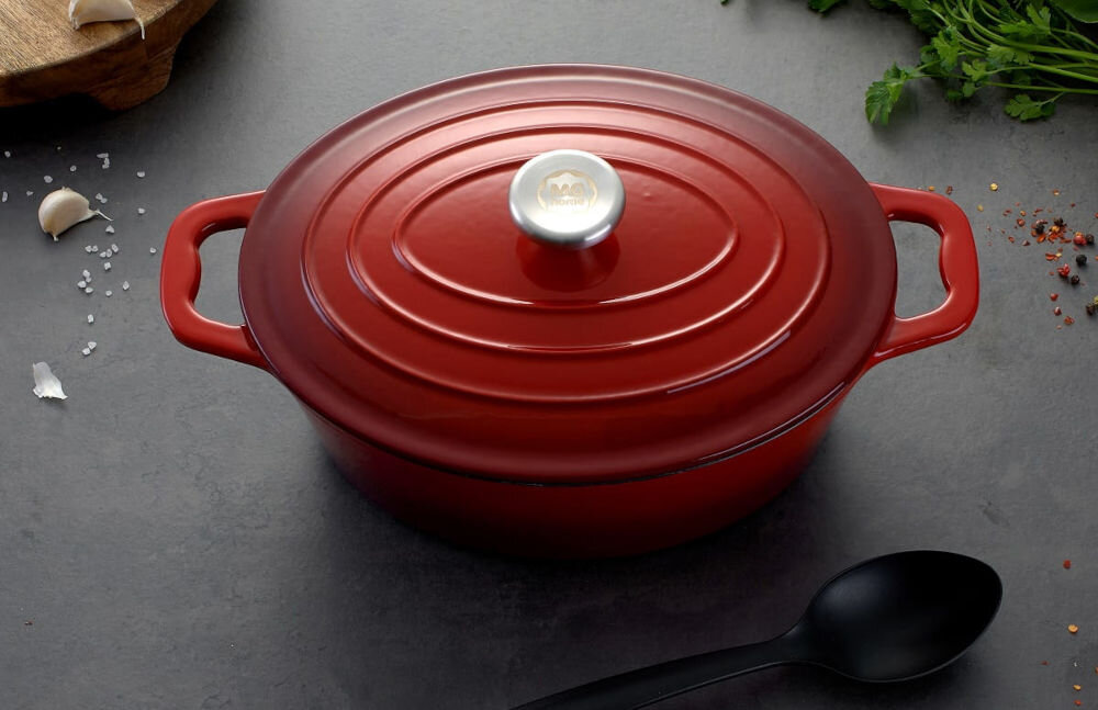 Brytfanna MG HOME Infinito 28 cm czerwona brytfanna stoi na ciemnym blacie zamknięta pokrywką łyżka leży obok 33,3 x 22 x 11 cm) średnica 28 cm pojemność 4 litrów jakość trwałość funkcjonalność w każdej kuchni solidne żeliwo pokryta emaliowaną powłoką wewnątrz do długiego gotowania duszenia oraz zapiekania w piekarniku  przystosowana do intensywnego użytkowania równomierne rozprowadzanie ciepła kontrolowanie procesu przygotowywania potraw wygoda praktyczne narzędzie kuchenne optymalne efekty gotowania  