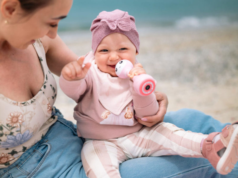 Zabawka edukacyjna ALILO Smarty Bunny R1 Niebieski towarzysz Twojego dziecka uroczy wygląd, rozwija zdolności poznawcze, przyjaciel, który wspiera rozwój i wywołuje uśmiech na 
					twarzy dziecka, dziewczynka na kolanach mamy z zabawką w ręce