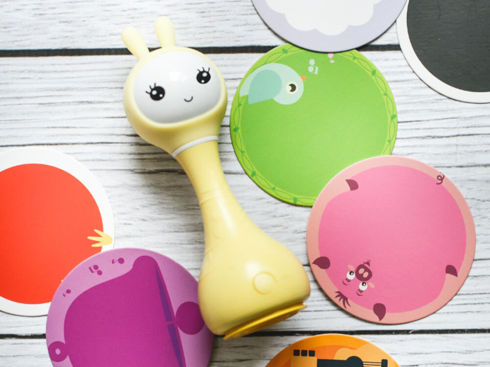 Zabawka edukacyjna ALILO Smarty Bunny R1 Niebieski interaktywna funkcja rozpoznawania kolorów, wspiera dziecko w poznawaniu kolorów w dwóch językach – polskim i angielskim,
					produkt w żółtym kolorze, dookoła kolorowe naklejki