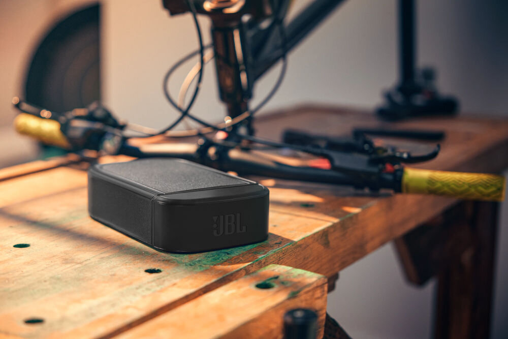 Soundbar JBL BAR 1000 MkII zasilanie 100-240 V akumulatory głośników energooszczędność, odłączony głośnik leżący na drewnianym blaciek obok roweru