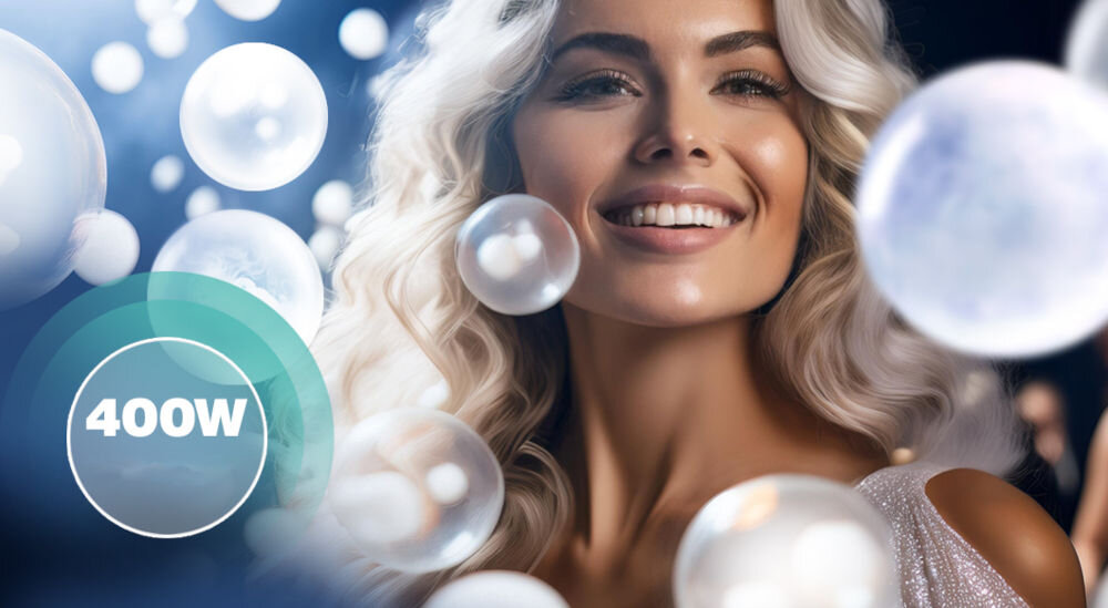 Osoba z długimi, falującymi włosami uśmiecha się, otoczona przez unoszące się bańki. Na obrazie widoczny jest napis \'400W\' w okręgu z zielonym obramowaniem.