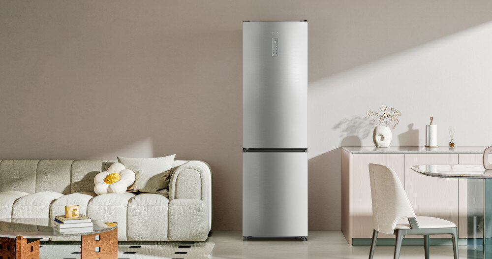 LODÓWKA DREAME COMBI MegaPro 2M-D DRB450WMBDEU NO FROST 201cm INOX Fotografia pokazuje lodówkę wolnostojącą w srebrnym wykończeniu ustawioną w przestrzeni dziennej, pomiędzy strefą wypoczynkową a jadalnią. Neutralne kolory wnętrza i miękkie światło dzienne eksponują prostą formę urządzenia oraz jego uniwersalny charakter – lodówka harmonijnie wpisuje się w styl wnętrza lodówka 456 l pojemna SpaceBoost energooszczędna cicha 39dB