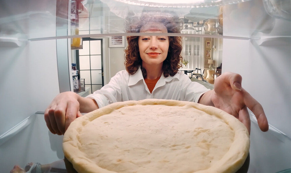 LODÓWKA DREAME COMBI MegaPro 2M-D DRB450WMBDEU NO FROST 201cm INOX Ujęcie wykonane z perspektywy wnętrza lodówki przedstawia osobę wkładającą gotowe danie na półkę. Widoczne są szklane półki oraz równomierne oświetlenie wnętrza. Zdjęcie akcentuje łatwy dostęp do produktów, ergonomię układu półek oraz komfort użytkowania funkcjonalne wnętrze pojemne półki szuflady organizacja duże produkty