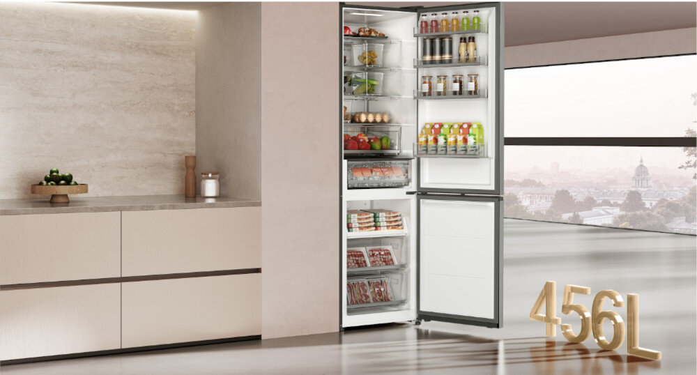 LODÓWKA DREAME COMBI MegaPro 2M-C DRB450WMBCEU NO FROST 201cm INOX Zdjęcie przedstawia lodówkę z otwartymi drzwiami, wypełnioną różnorodnymi produktami spożywczymi: owocami, warzywami, napojami i gotowymi daniami. Obok widnieje oznaczenie pojemności „456L”. Ujęcie podkreśla dużą pojemność oraz logiczne rozmieszczenie przestrzeni wewnętrznej SpaceBoost duża pojemność 409l więcej miejsca zapasy