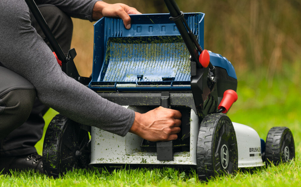 Kosiarka akumulatorowa BOSCH Professional GRA18V2-46SP 06008C8200 trawnik osoba wkłada przystawkę do mulczowania do kosiarki funkcja mulczowania rozdrabnia skoszoną trawę równomiernie rozprowadza ją na trawniku przystawka w zestawie naturalny nawóz