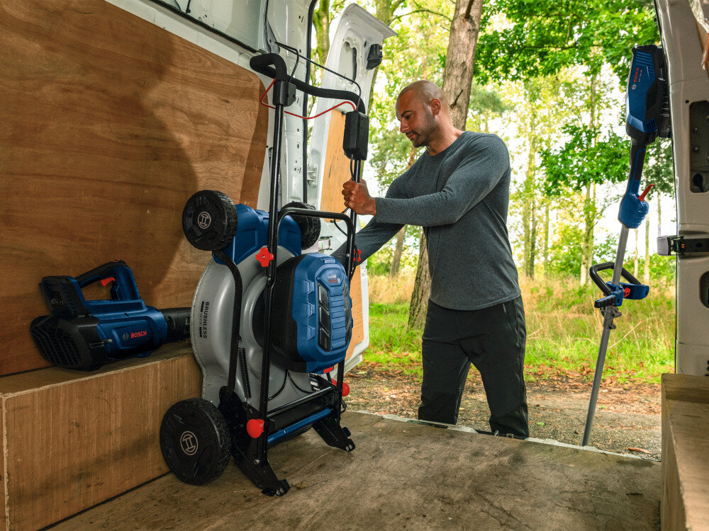 Kosiarka akumulatorowa BOSCH Professional GRA18V2-46SP 06008C8200 wnętrze samochodu dostawczego osoba wkłada złożoną kosiarkę do wnętrza składany uchwyt możliwość przechowywania w pozycji pionowej waga 31,5 kg stabilne podczas koszenia komfort i precyzja pracy