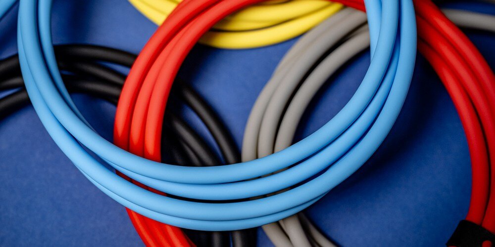 Kobieca dłoń wpina silikonowy kabel Newell USB-C do USB-C do leżącej na drewnianym blacie ładowarki.