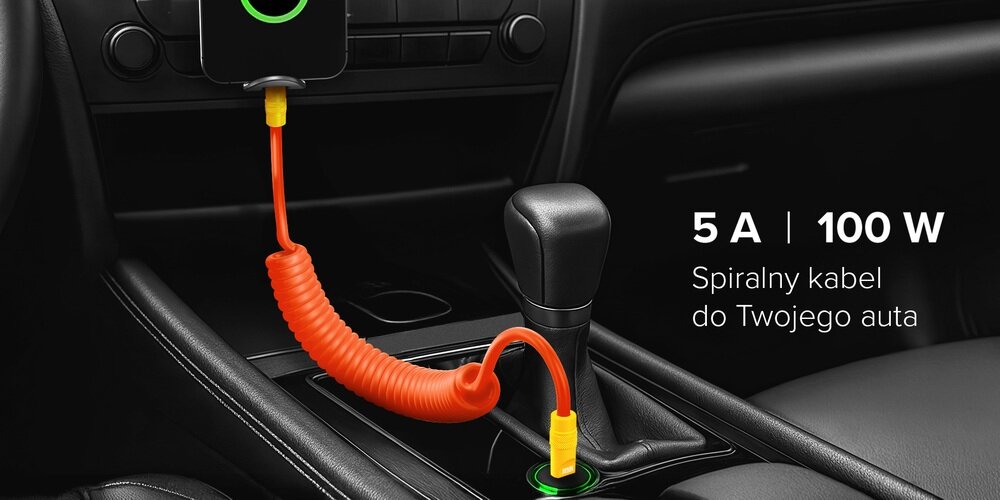 Kabel Newell USB-C - USB-C 100 W, 1,5m, silikonowy, spiralny, na drewnianym blacie pośród sprzętów do ładowania.