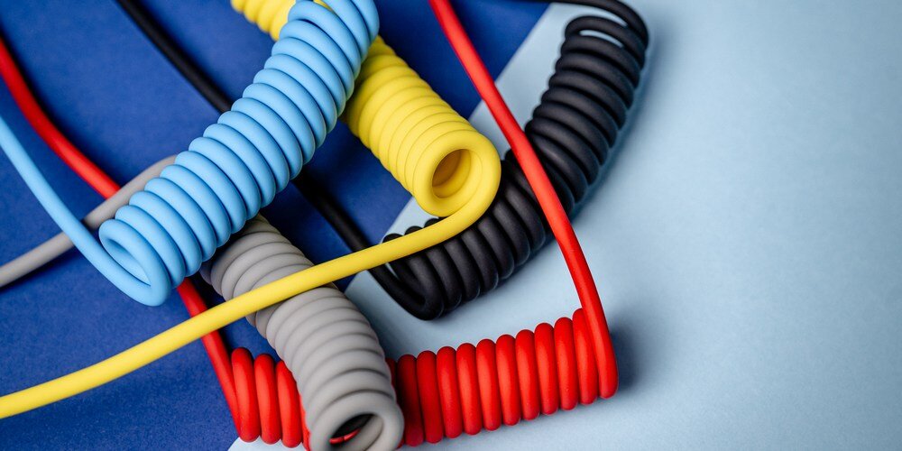  kabel Newell USB-C - USB-C 100 W, 1,5m w dwóch wersjach: spiralnej, pod nią wyprostowanej, na niebieskim tle.