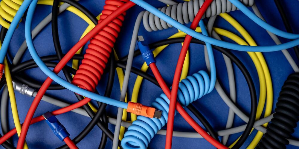Poplątane różne kolorowe kable marki Newell, spiralne i proste.