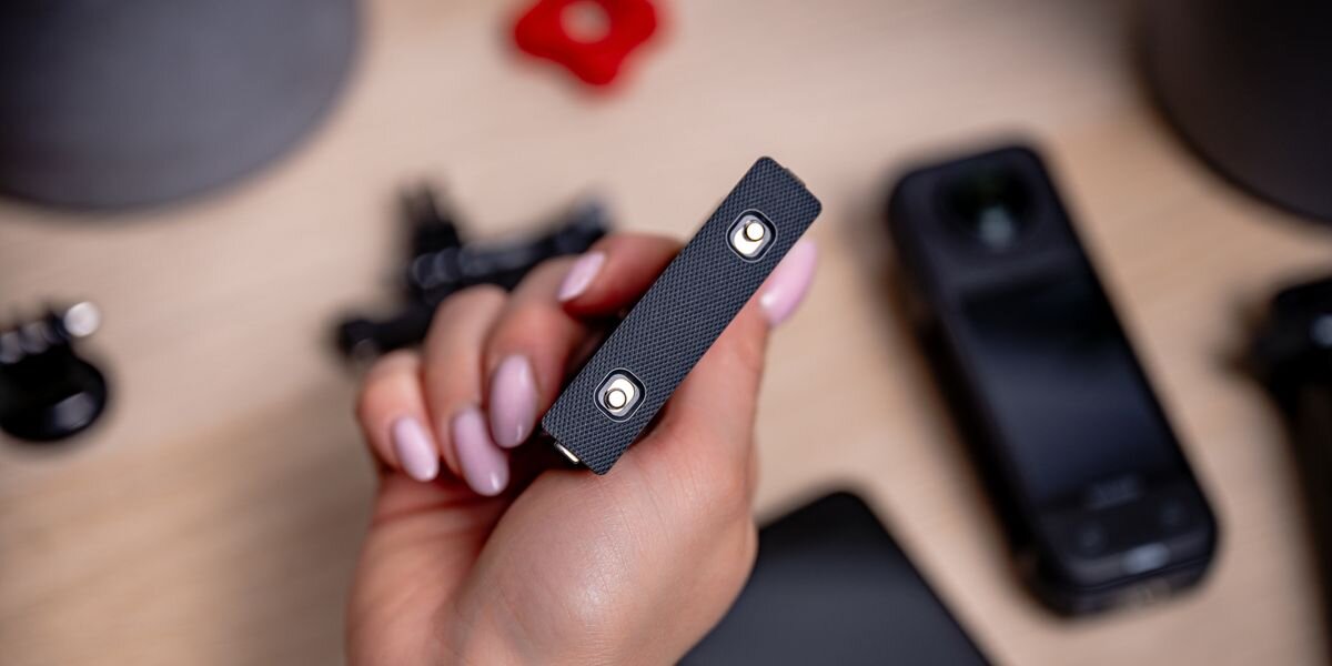 Akumulator NEWELL 2350 mAh Cinsbbma do Insta360 X4, Zbliżenie na spód baterii Newell trzymanej w dłoni. Widoczne dwa metalowe styki ładowania na teksturowanej powierzchni, szybkie, ładowarka, kompatybilny, odzyskiwanie