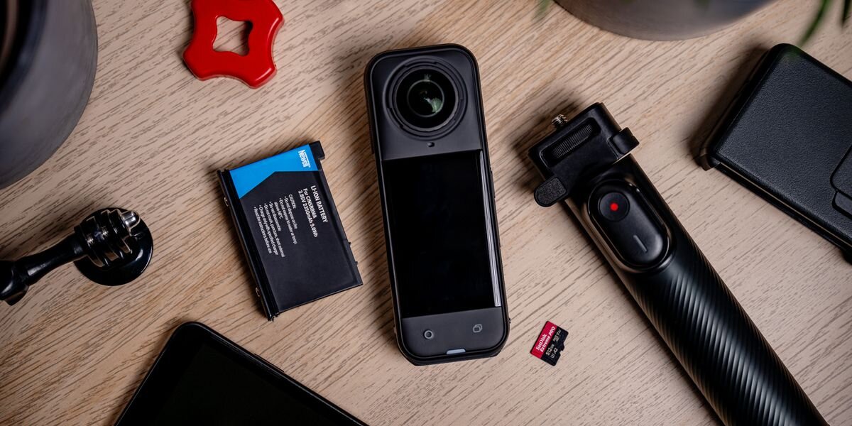 Akumulator NEWELL 2350 mAh Cinsbbma do Insta360 X4, Kamera 360, bateria Newell, karta SanDisk i statyw ułożone na jasnym, drewnianym blacie. Widok z góry, testy, jakość, gwarancja, żywotność
