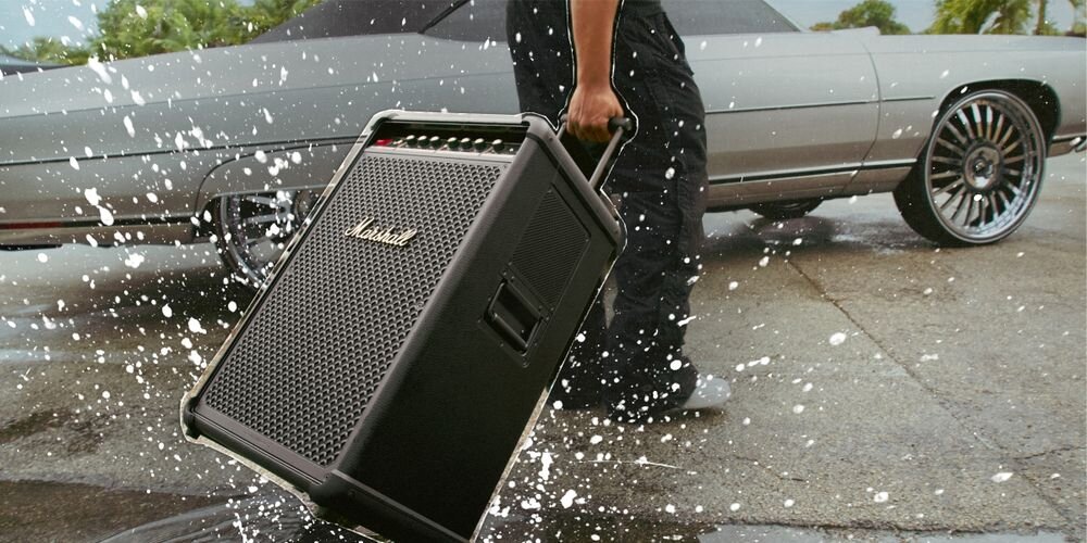 Power Audio MARSHALL Bromley 750 klasa IP54 odporność na kurz zachlapania użytkowanie na zewnątrz, osoba trzymająca głośnik za uchwyt