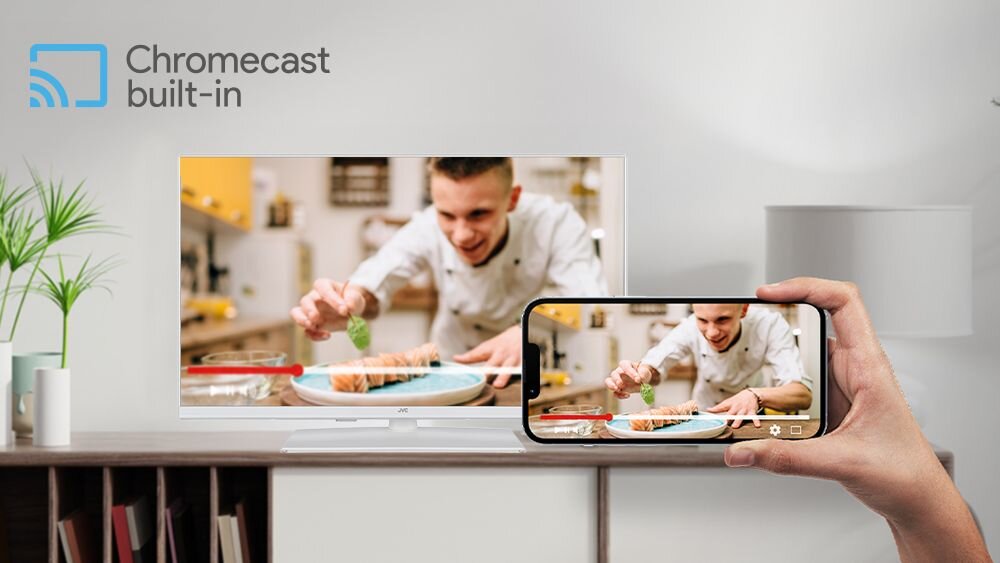 Telewizor JVC LT-32VAF330W Google Chromecast udostępnianie treści z telefonu, telewizor stojący na komodzie w pomieszczeniu, ręka trzymająca smartfona