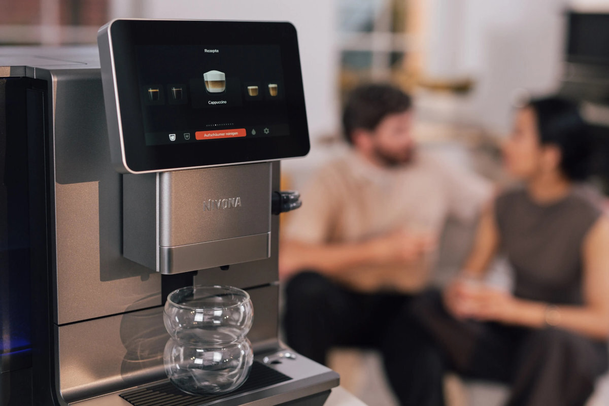 NIVONA Nivo 9103 - ekspres z pustą szklanką, w tle dwie osoby