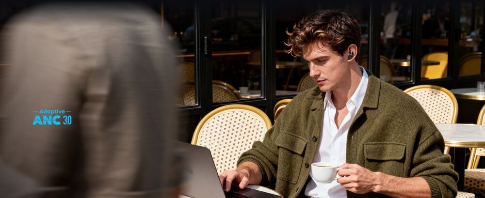 Słuchawki douszne SOUNDCORE Liberty Buds ANC półdouszna konstrukcja wkładki komfort, osoba z założonymi słuchawkami pijąca kawę