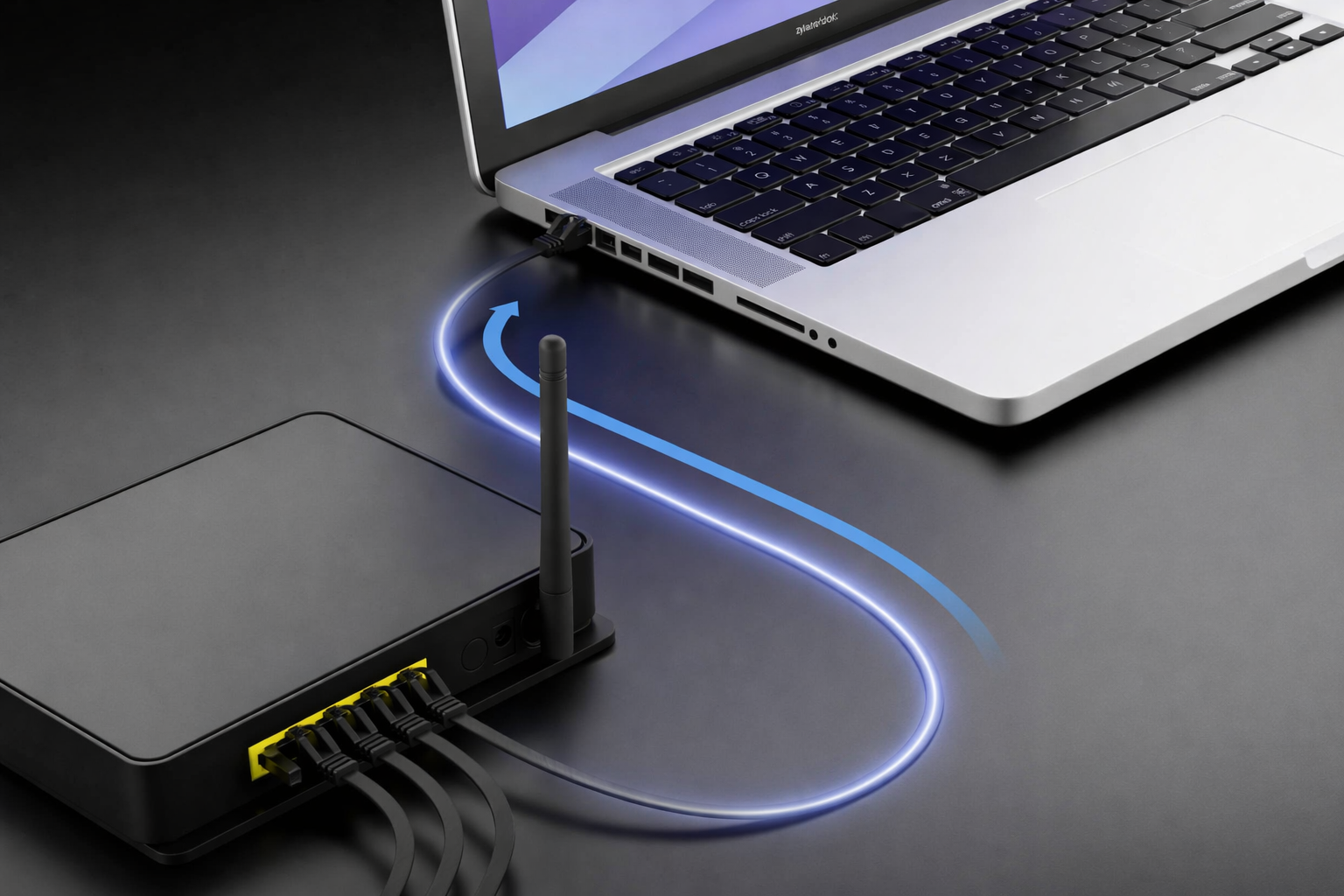 Na obrazie widać laptopa podłączonego do routera za pomocą kabla sieciowego. Na laptopie widoczny jest napis \'Realforce\'.