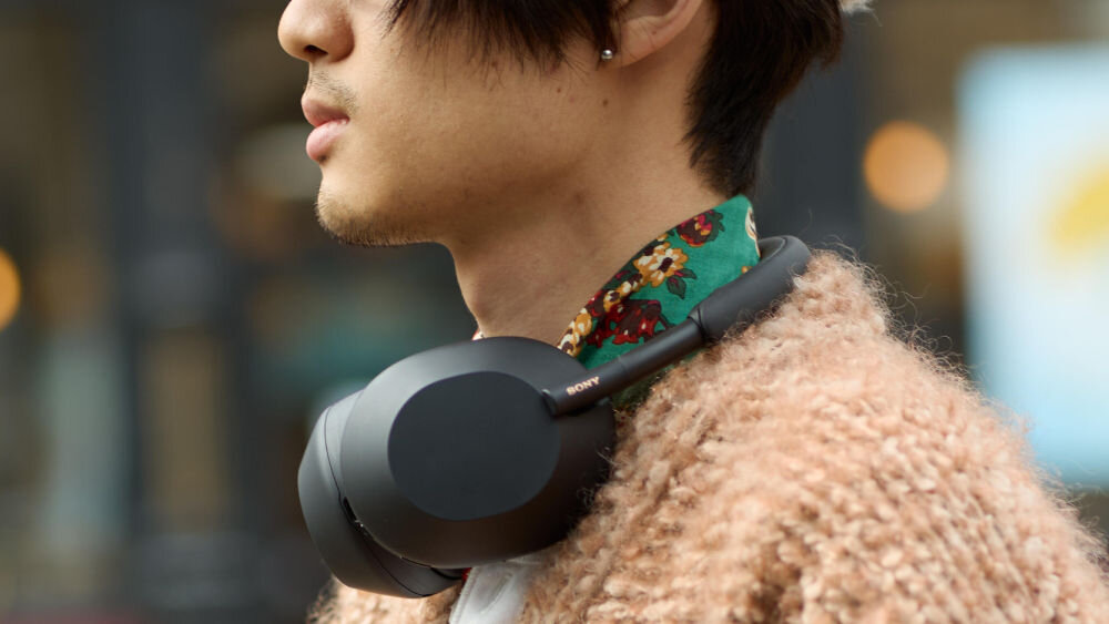 Słuchawki nauszne SONY WH-1000XM5SA z Hi-Resolution Audio i czystym dźwiękiem, osoba z przewieszonymi słuchawkami na szyi