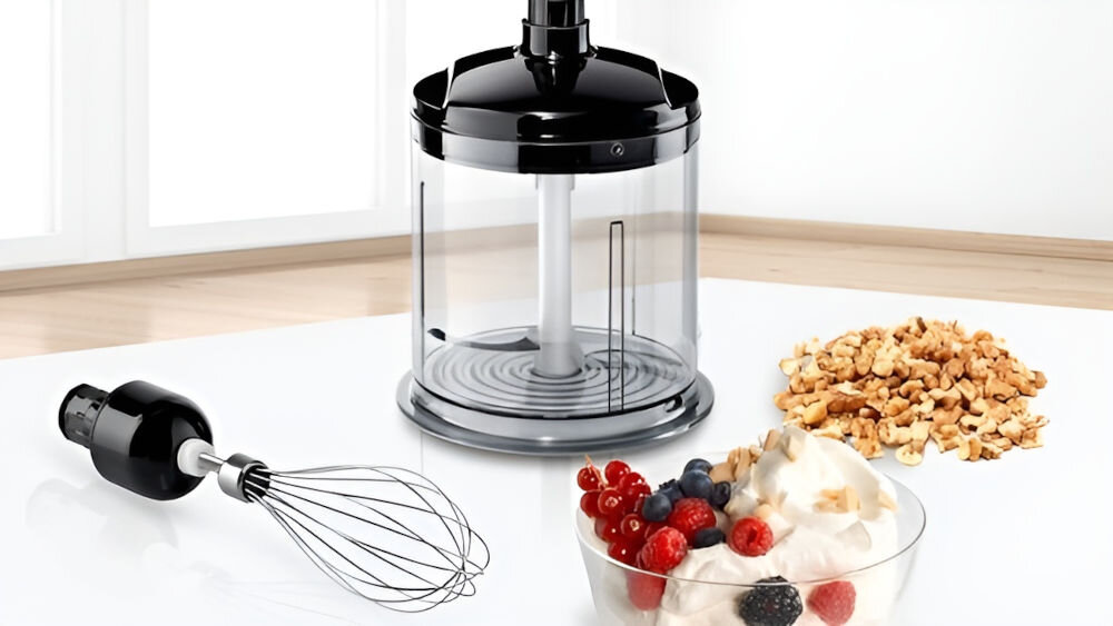 Blender BOSCH ErgoMixx MS61B6150 rozdrabniacz przezroczysty zbiornik czarna góra ostrze bok lezy końcówka ubijająca rozdrobnione orzechy deser w szkle rozdrabniacz szybkie siekanie składników zioła orzechy mięsa cebula oszczędność czasu końcówka do ubijania przygotowanie lekkich kremów puszystej piany z białek optymalnie ubita śmietana łatwe przyjemne kulinarne wyzwania  