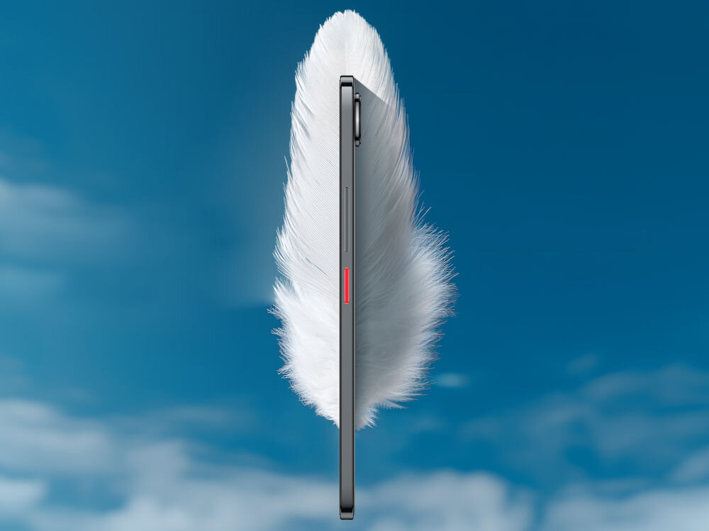 Smartfon NUBIA Air 8/256GB 6.78 120Hz Smartfon nubia, w kolorze ciemnoszarym, widoczny z boku (profilu), jest włożony w białe, puszyste pióro, symbolizując lekkość. Widać czerwony przycisk z boku. Tło to błękitne niebo z chmurami.