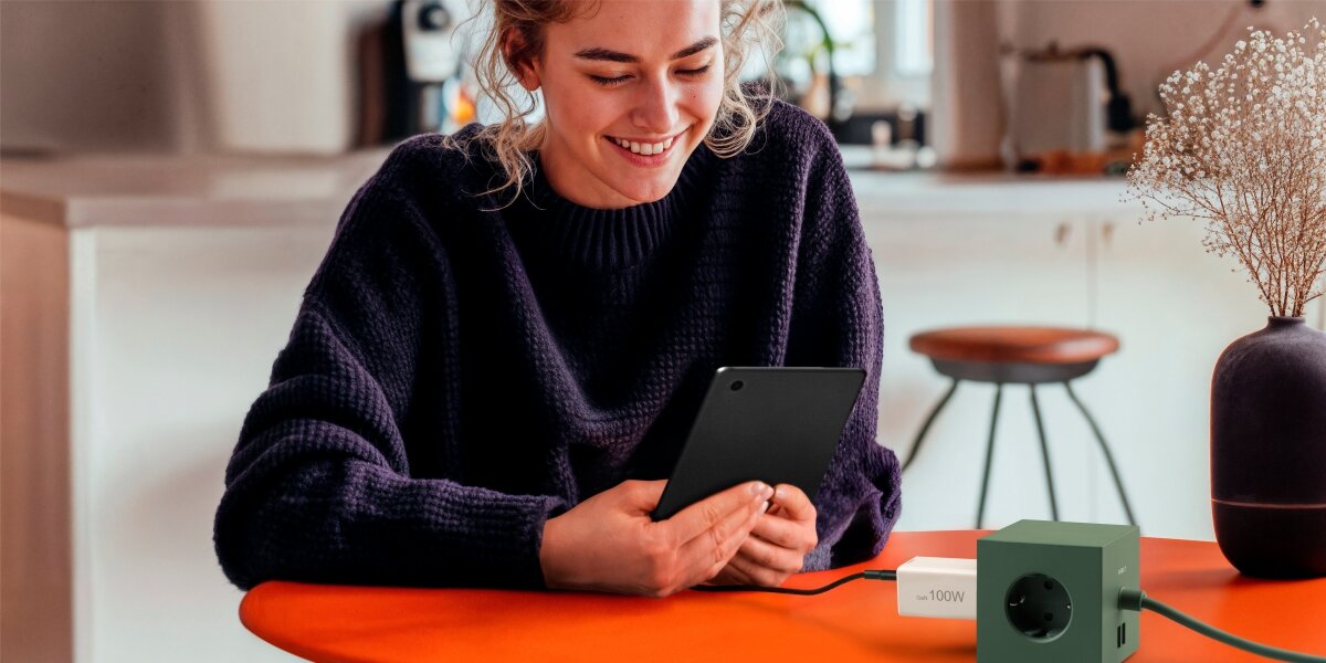 Ładowarka sieciowa HAMA 100W GaN PD/QC, 2x USB-C, 1x USB-A Zbliżenie na dłoń trzymającą czarny transmiter FM Hama z niebieskim podświetleniem LED, wyświetlający częstotliwość 106.2.