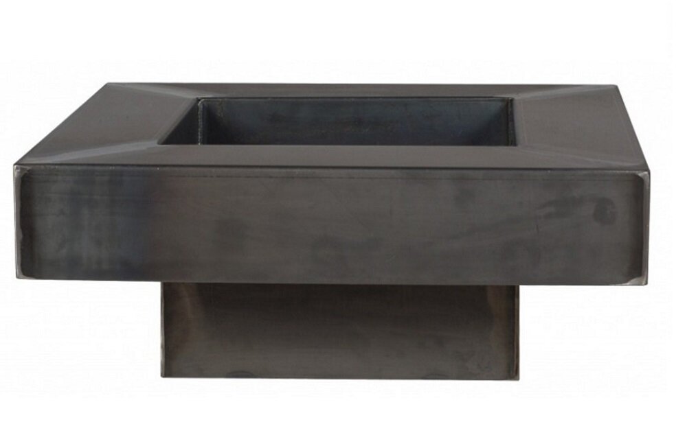 Na obrazie widoczne jest metalowe palenisko ogrodowe o prostokątnym kształcie z szerokim rantem. Palenisko ma ciemny kolor i stoi na prostokątnej podstawie.