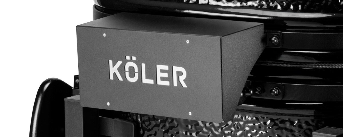 Grill węglowy KOLER Kamado EG23, zawias, pokrywa, jedna, ręka, na białym tle zbliżenie na logotyp przymocowany do grilla