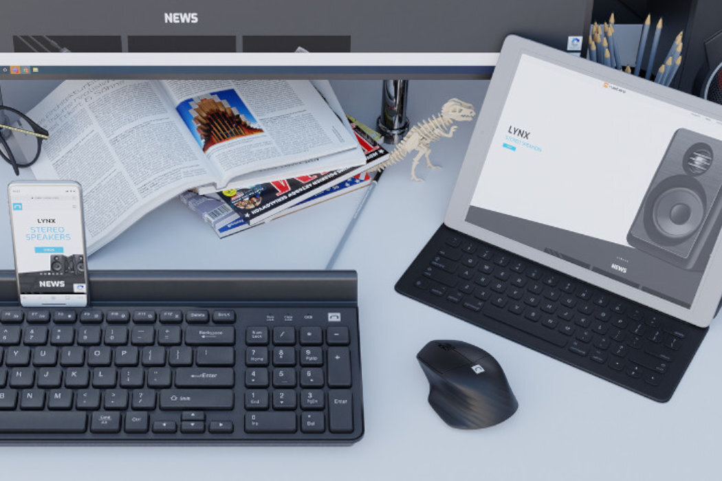 Na biurku znajduje się klawiatura, myszka oraz tablet z wyświetlonym obrazem głośników i napisem \'LYNX STEREO SPEAKERS\'. Obok leży otwarta książka i kilka magazynów, a na ekranie monitora widoczny jest napis \'NEWS\'.