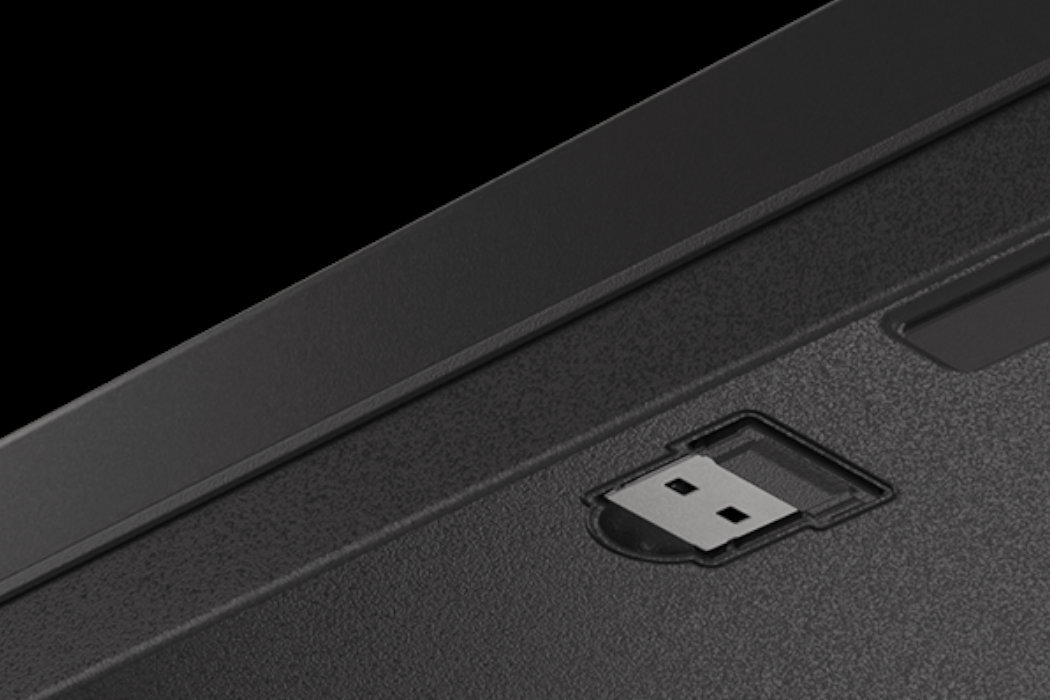 Zbliżenie na czarną powierzchnię z wbudowanym portem USB. W tle widoczny jest fragment obudowy urządzenia.