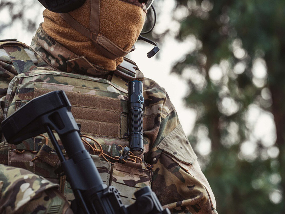 Latarka OLIGHT Warrior 3S OL125538 Czarny, przyciski, funkcjonalność, taktyka, ergonomia, Operator w kamuflażu z latarką na kamizelce